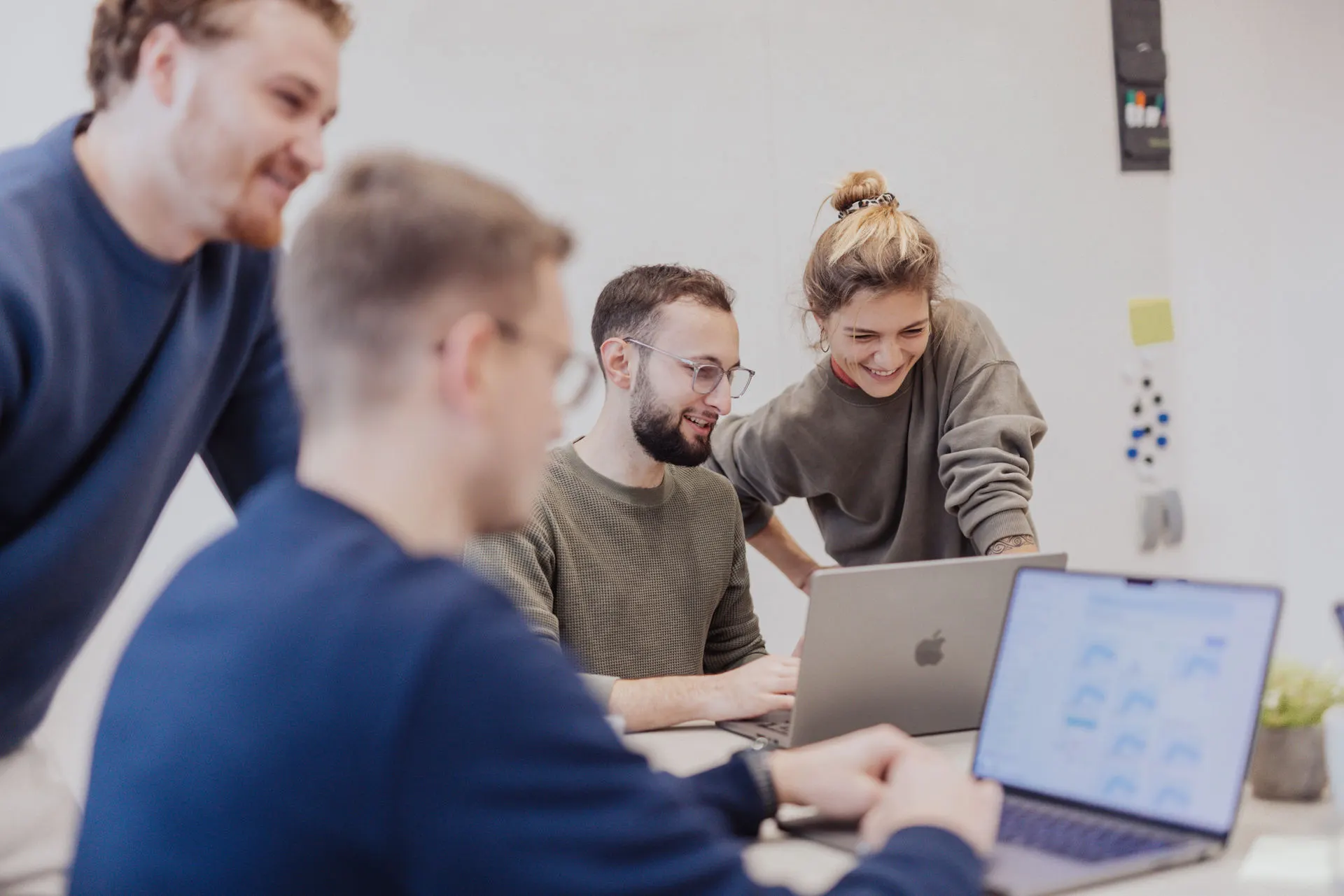 Vier Personen aus dem O/WONDER-Team schauen gemeinsam auf einen Laptop-Bildschirm